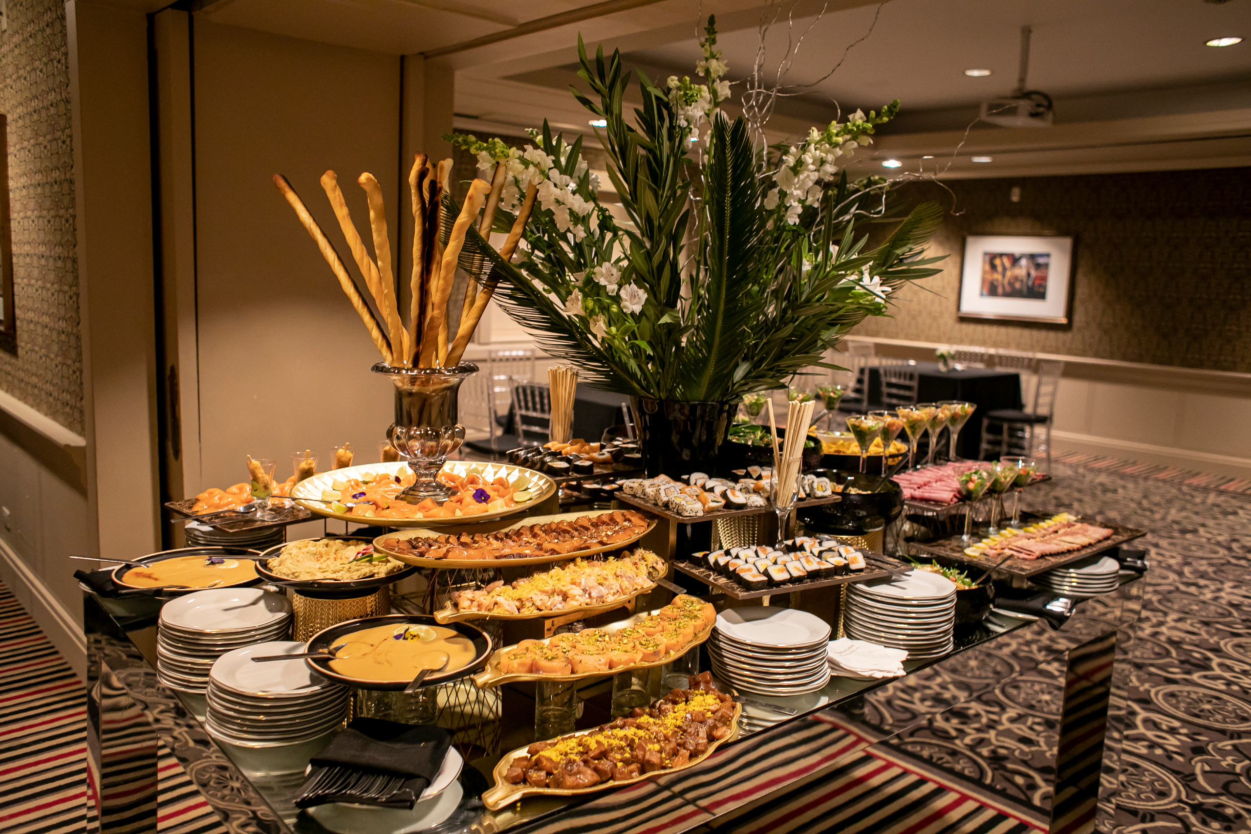 Mesa de catering con sushi, entradas y centro de flores